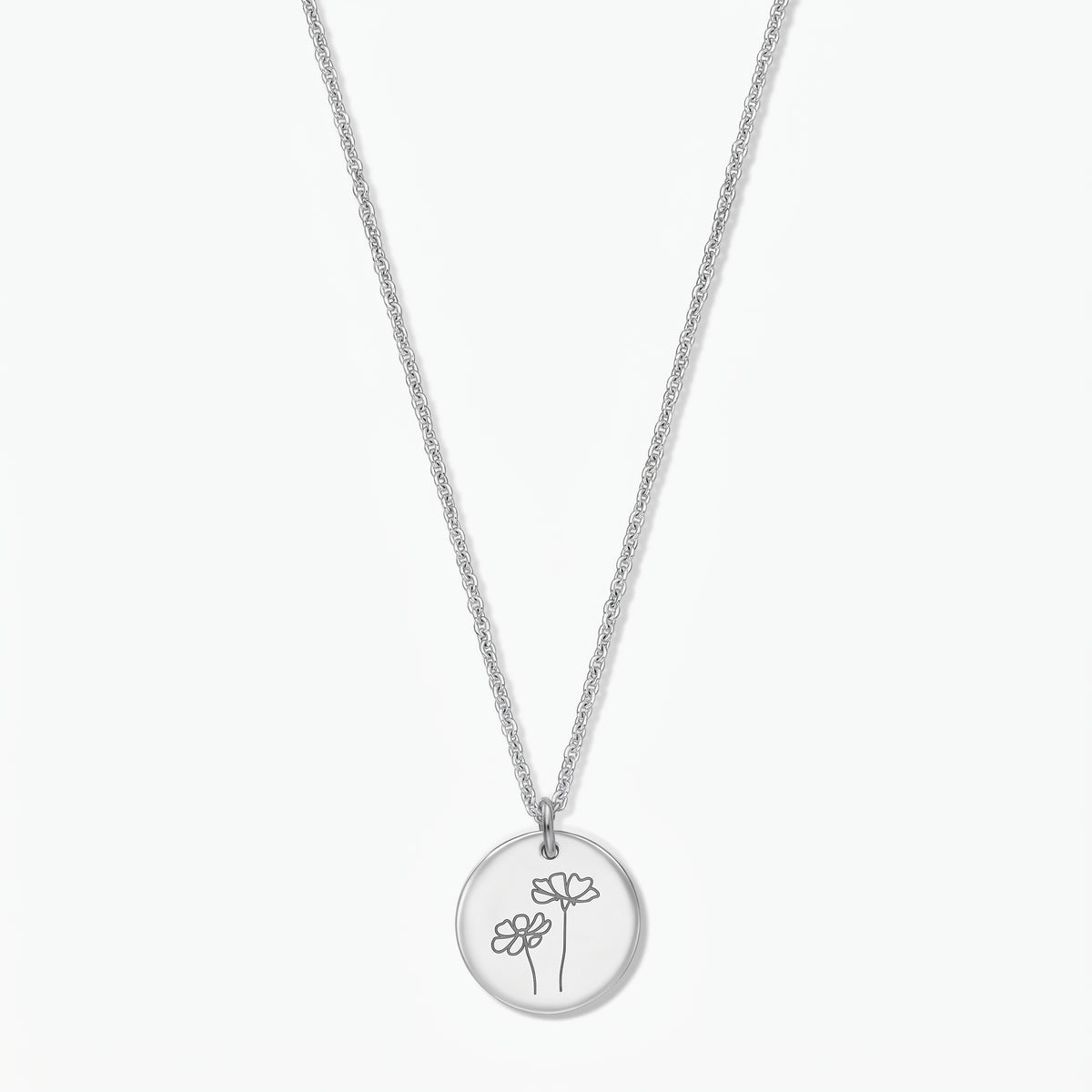 Sterling silver birthflower necklace for October (Cosmos) by Indira, with a round disc pendant engraved with two cosmos flowers on a fine silver chain, isolated on a white background.