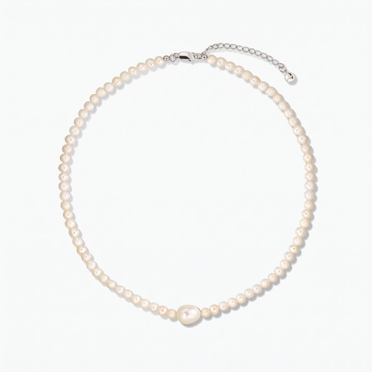 Cultured pearl necklace with a larger center pearl and a silver clasp with extender, photographed on a white background.