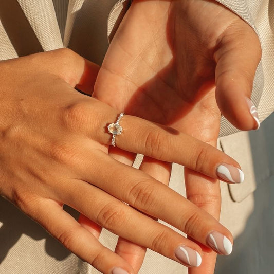 Hands showcasing a Selah Silver Ring with a moonstone against a soft background.