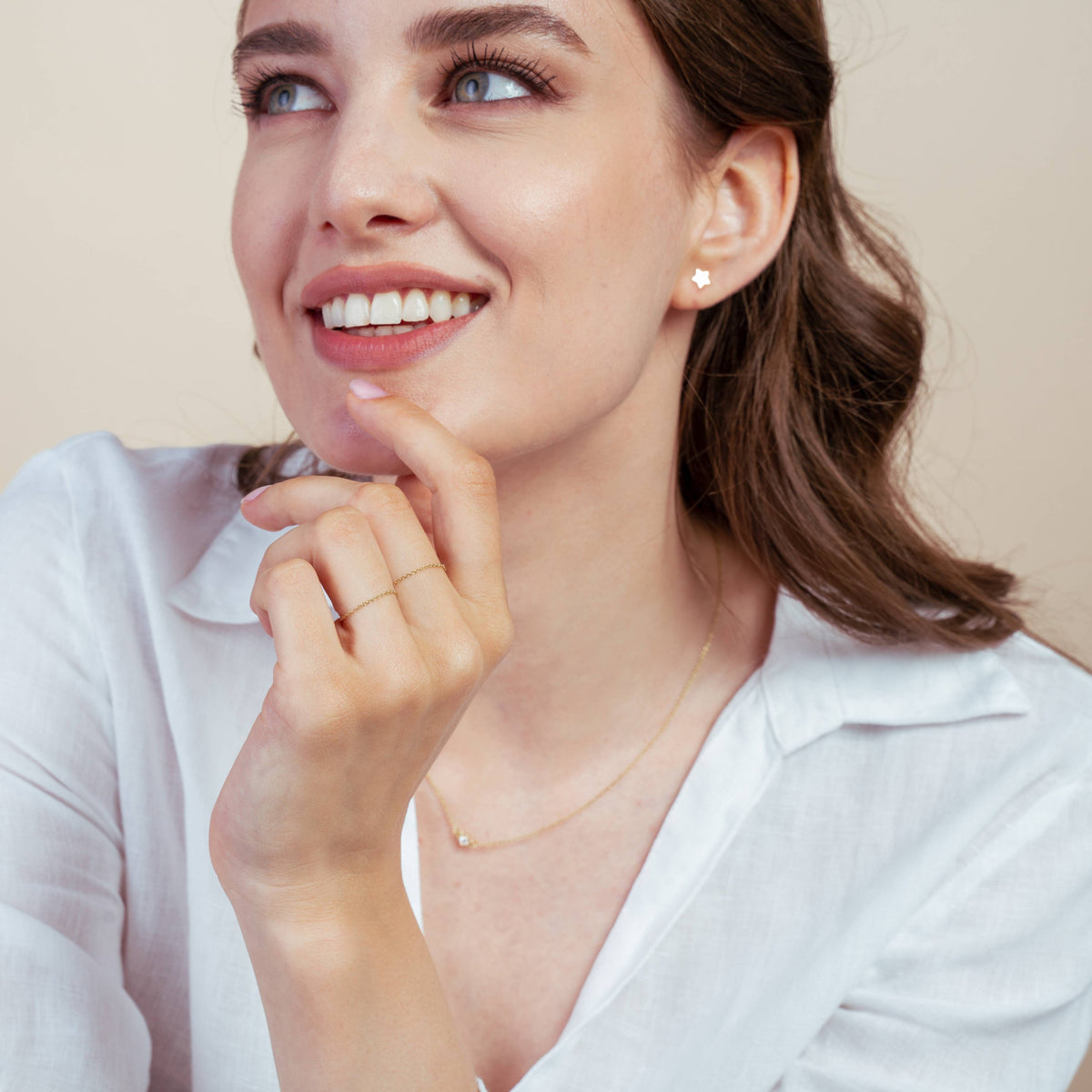 Smiling woman wearing 14K gold star earrings, white shirt, and gold necklace.