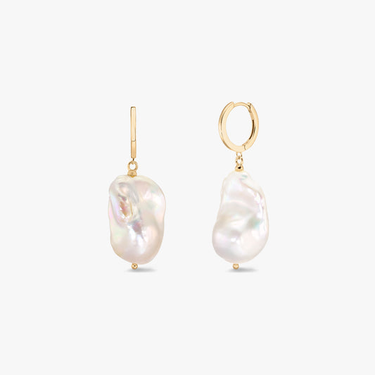 Pair of gold-plated hoop earrings with organic baroque white pearls on a white background.