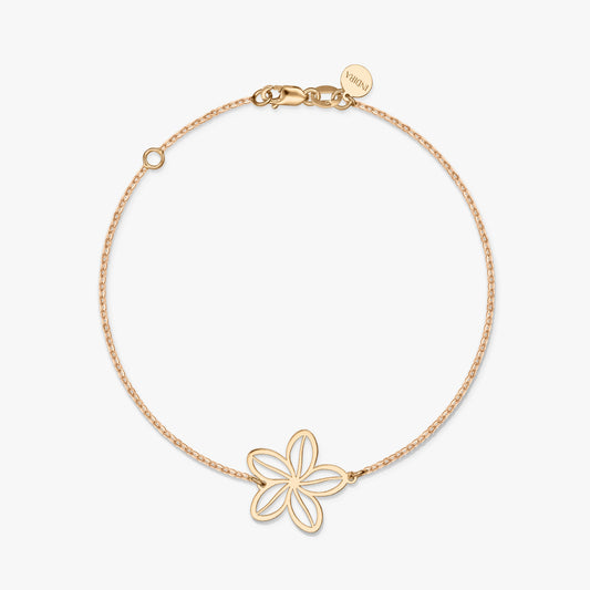 A minimalist gold bracelet featuring a delicate flower charm on a solid white background.
