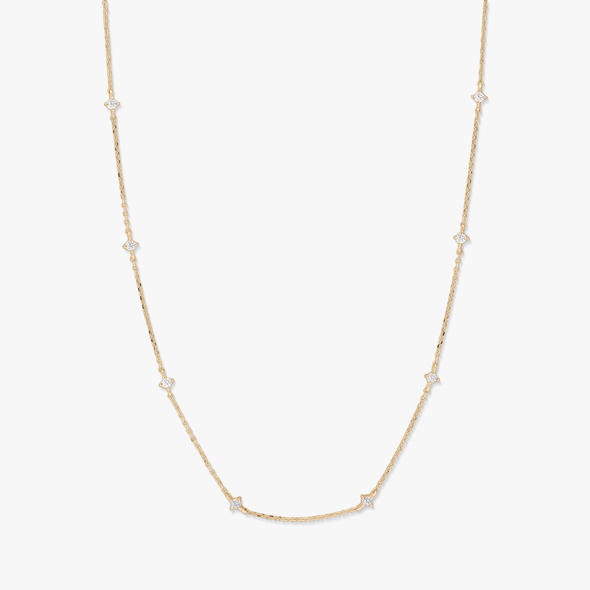 Delicate 14K yellow gold station necklace with small starburst-shaped white zirconia accents spaced along a fine chain, photographed on a white background.
