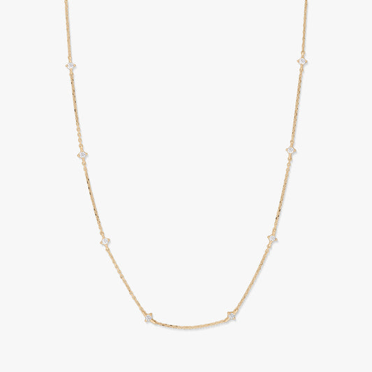 Delicate 14K yellow gold station necklace with small starburst-shaped white zirconia accents spaced along a fine chain, photographed on a white background.