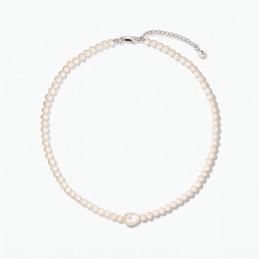 Cultured pearl necklace with a larger center pearl and a silver clasp with extender, photographed on a white background.