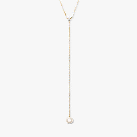 Minimalist gold lariat necklace with a single round white pearl drop and small accent stone, centered on a white background.