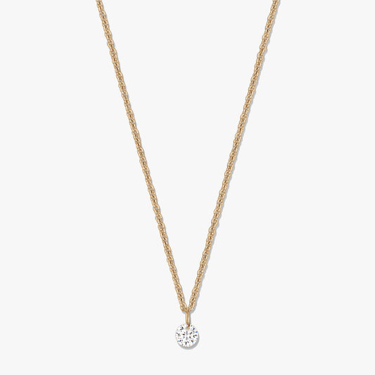 Gold‑tone silver necklace with a single round clear zirconia solitaire pendant on a white background.