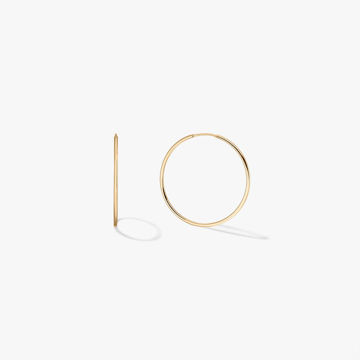 Pair of mini 14k yellow gold hoop earrings on a white background, one shown front-on and one in side profile.