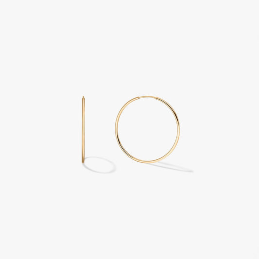 Pair of mini 14k yellow gold hoop earrings on a white background, one shown front-on and one in side profile.