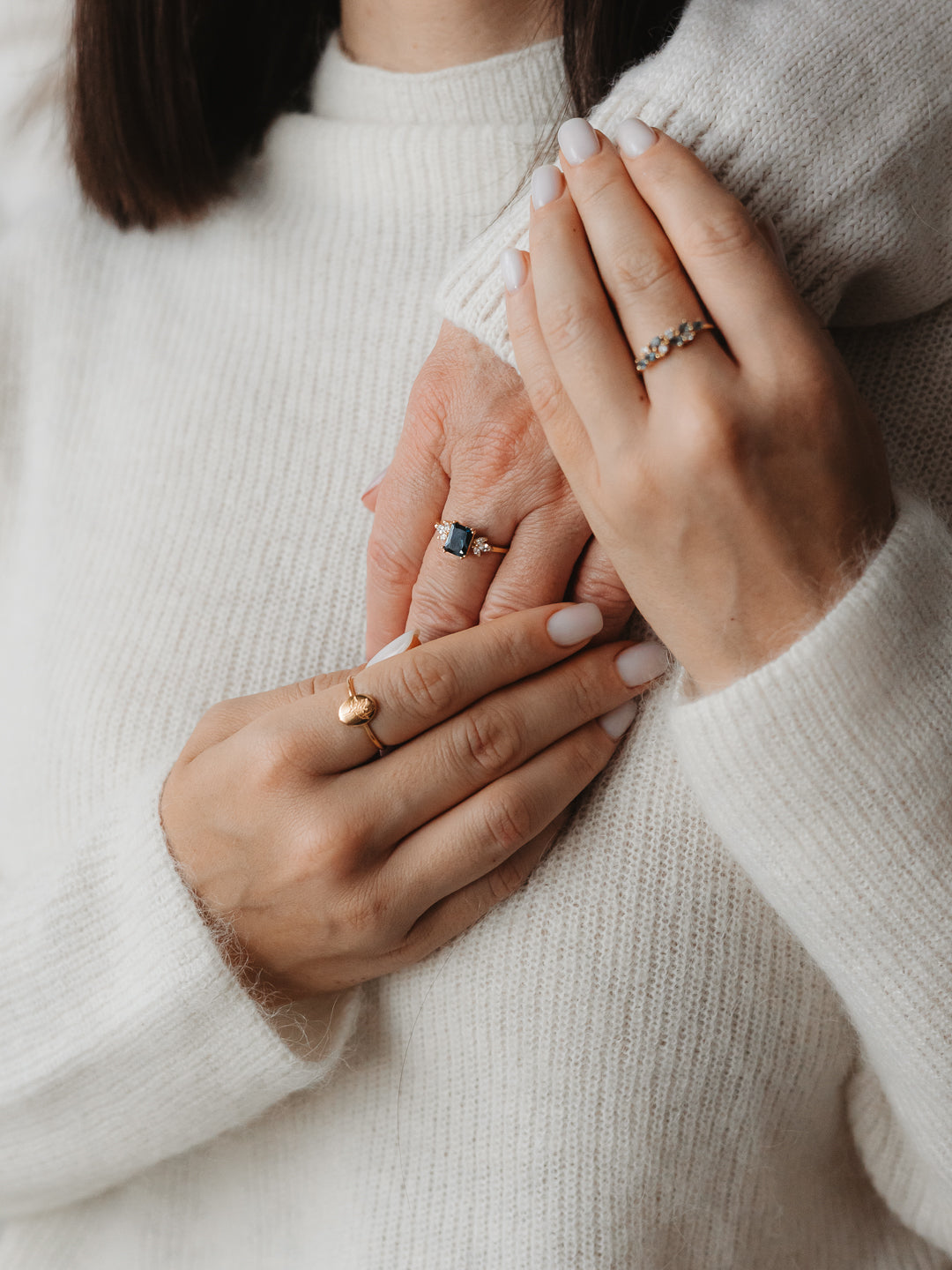 Close-up of hands showing elegant rings with blue topaz and gold accents.