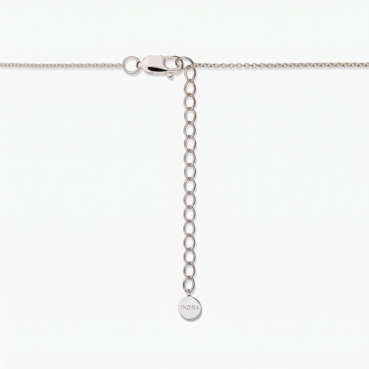 Close-up of a sterling silver necklace clasp with an adjustable extender chain and a small round tag engraved “INDIRA,” on a white background.