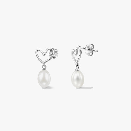 Pair of sterling silver heart stud earrings with dangling natural white pearls on a white background.