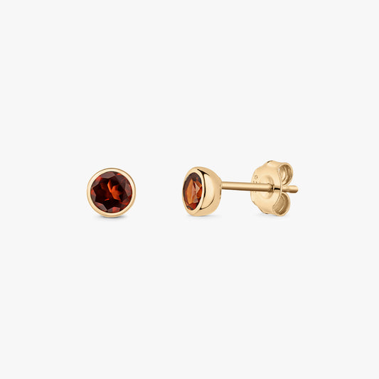 Pair of gold-plated sterling silver stud earrings with round faceted garnet birthstones, bezel set with butterfly backs, on a white background.