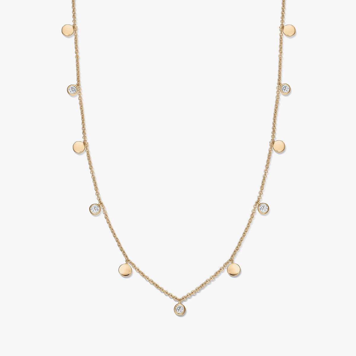 Gold‑plated sterling silver station necklace with alternating small polished disc charms and bezel‑set white topaz on a delicate chain, photographed on a white background.
