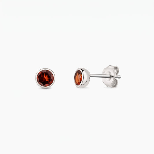 Pair of sterling silver stud earrings with round garnet stones shown front and side on a white background, with butterfly backs visible.