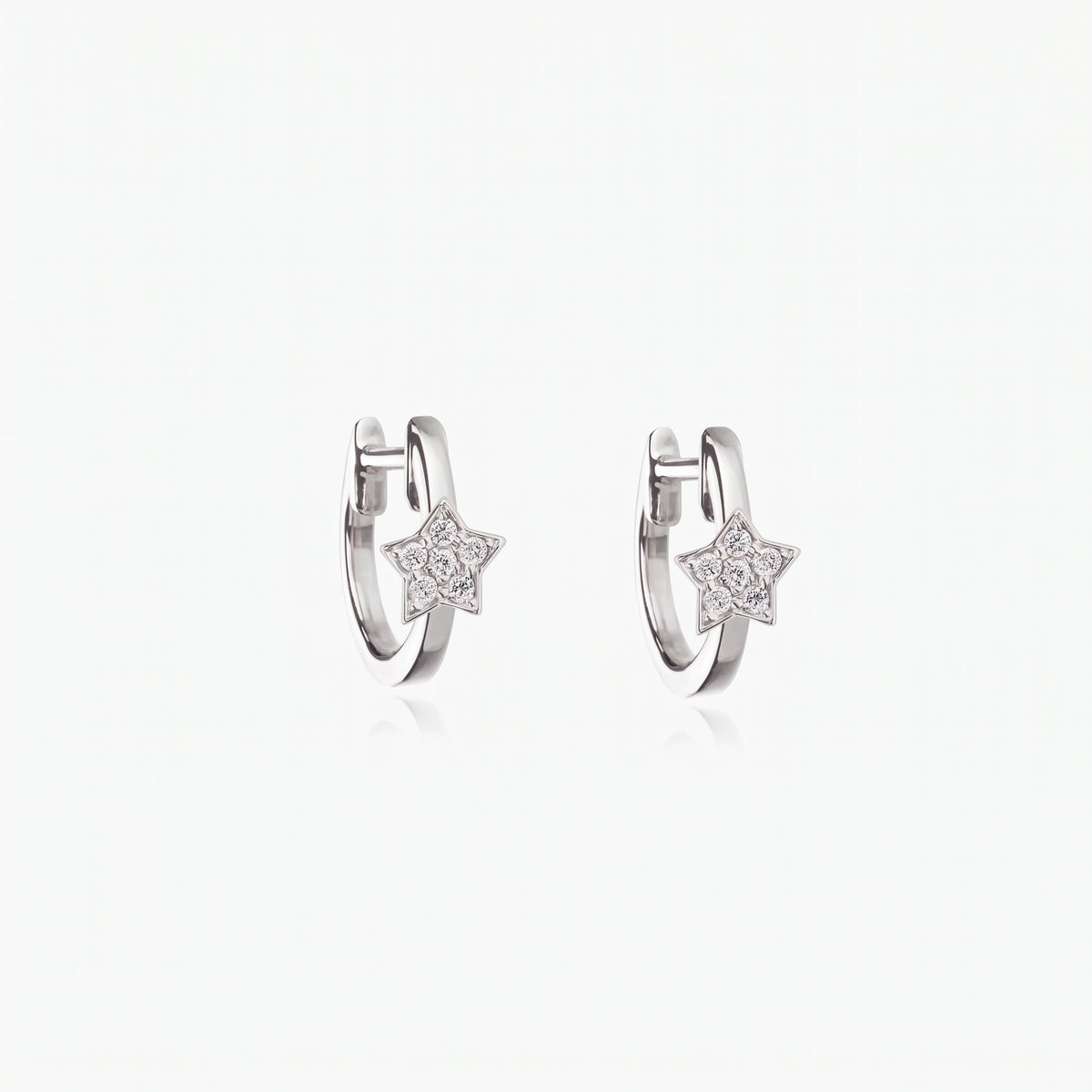 Pair of rhodium-plated 925 sterling silver huggie hoop earrings with small star charms set with clear zirconia on a white background.