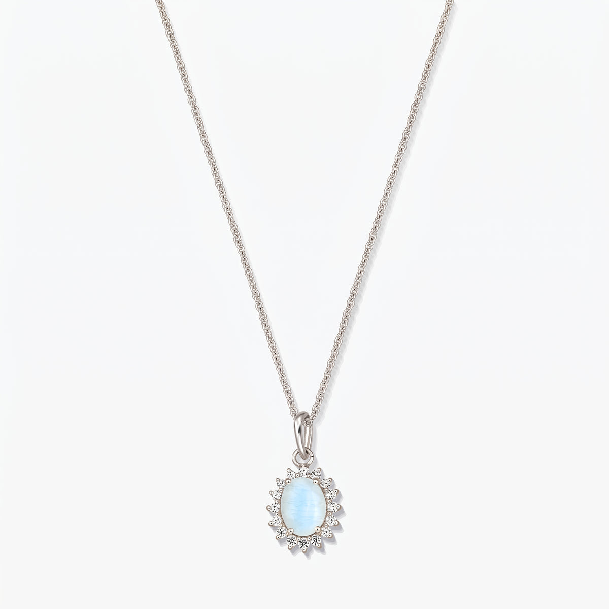 Sterling silver necklace with an oval light‑blue moonstone pendant framed by small clear stones on a fine chain, photographed on a white background.