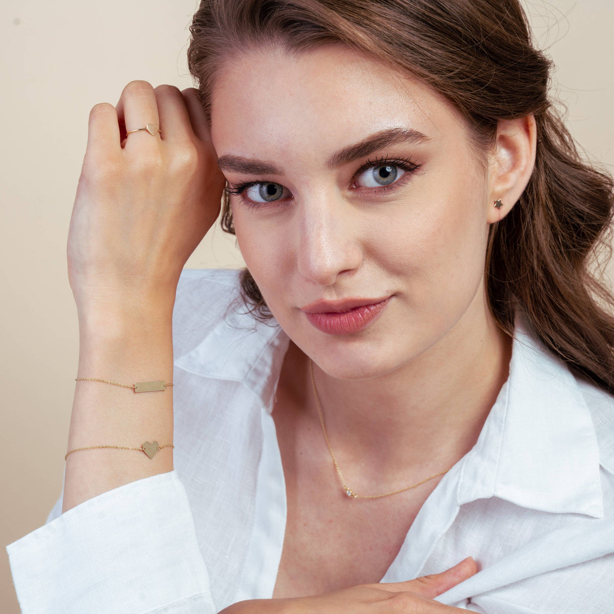 Woman wearing gold jewelry including earrings, bracelets, necklace, and a ring