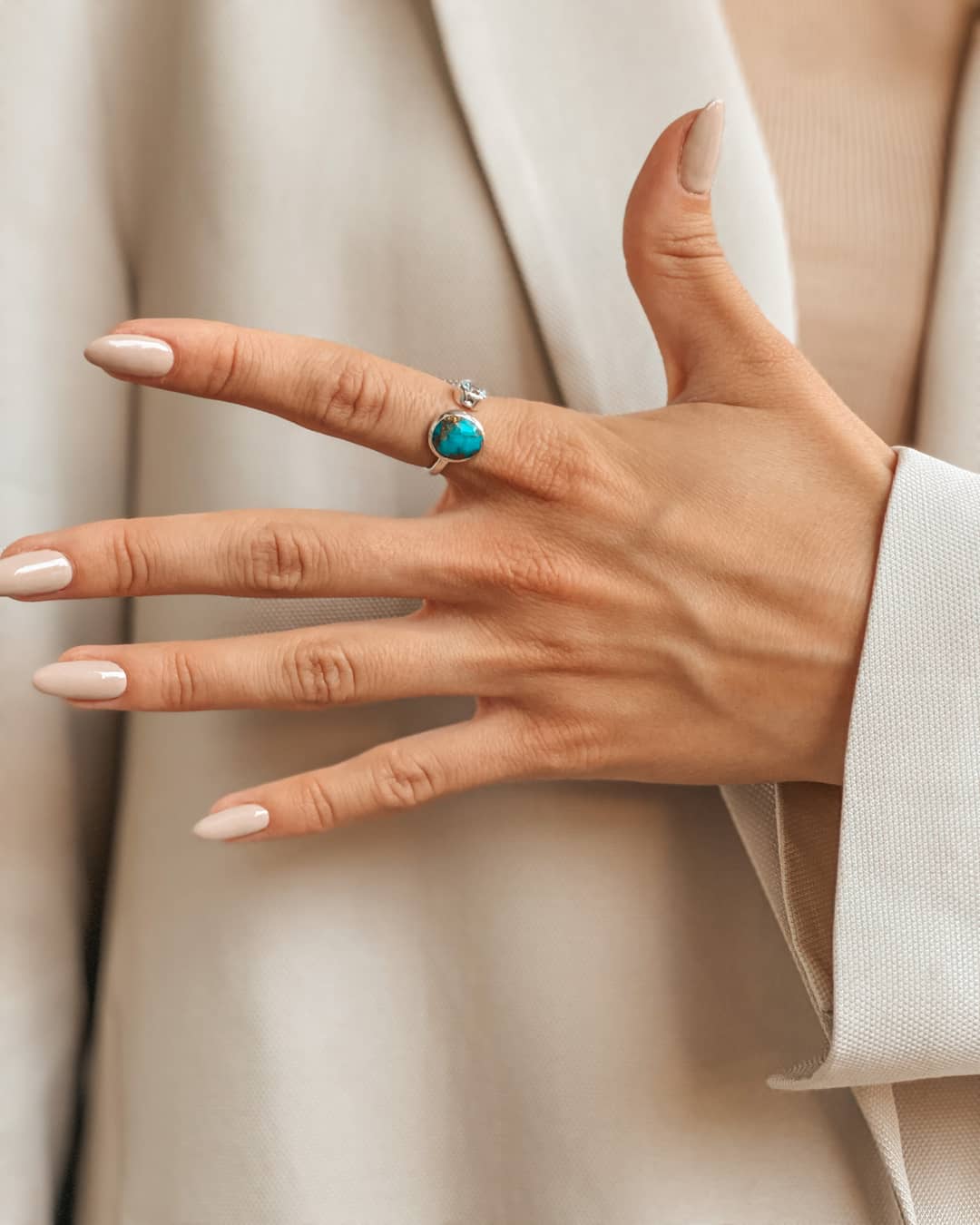 Close-up of a hand wearing a silver ring with blue topaz and turquoise.